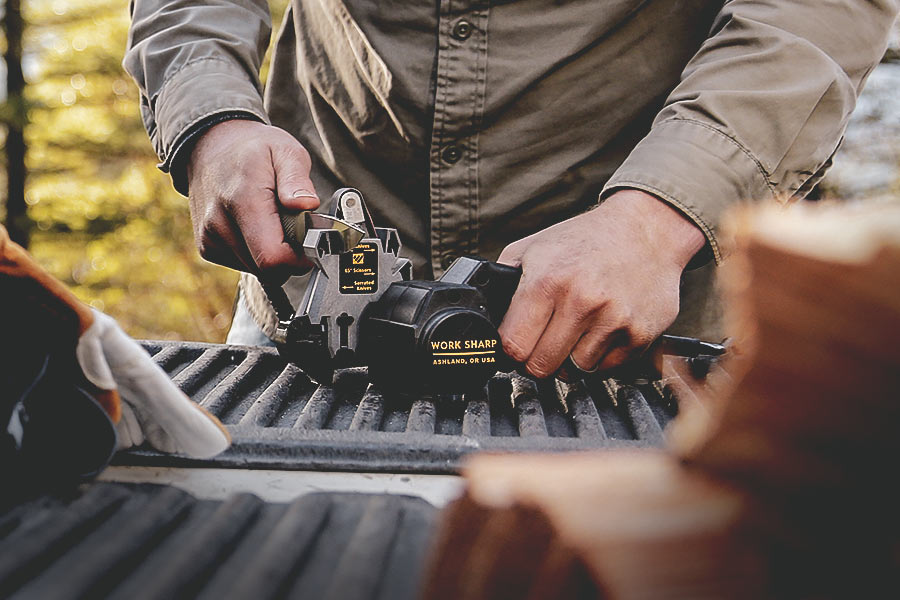 Man sharpening a pocket knife in the Work Sharp Knife and Tool Sharpener on the back of a tale gate