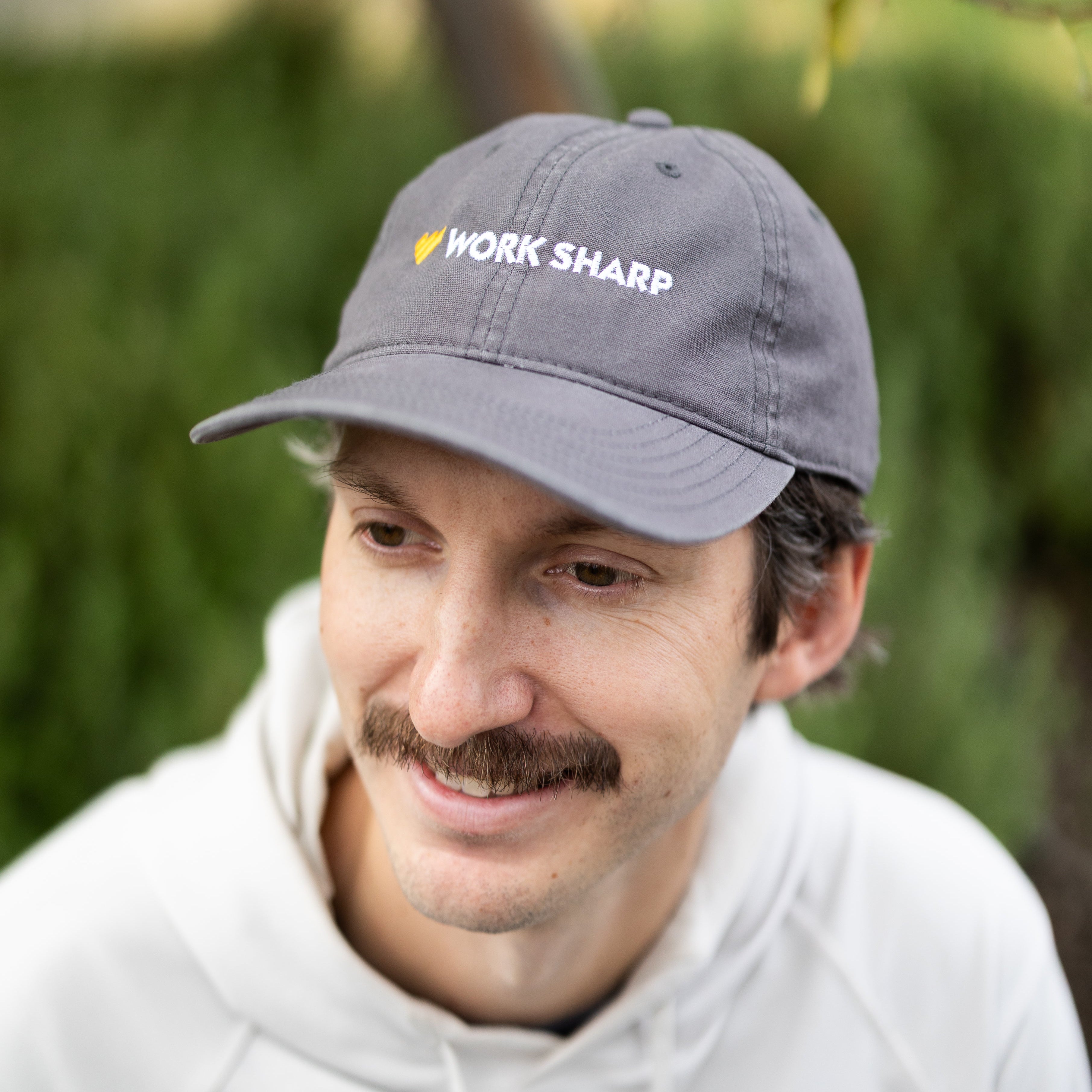 Man wearing a gray cap with 'Work Sharp' logo outdoors