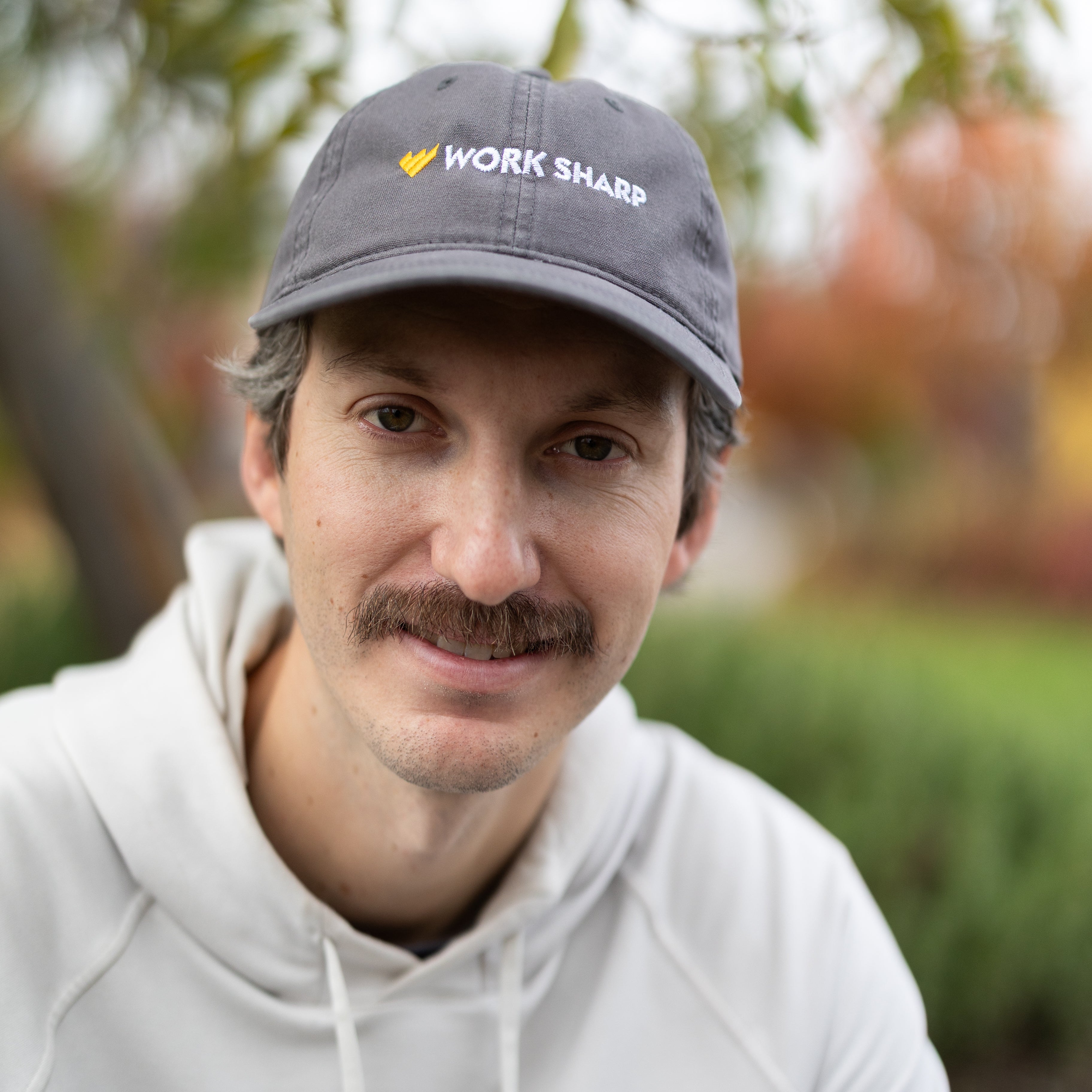 Man wearing a cap with 'Work Sharp' logo outdoors