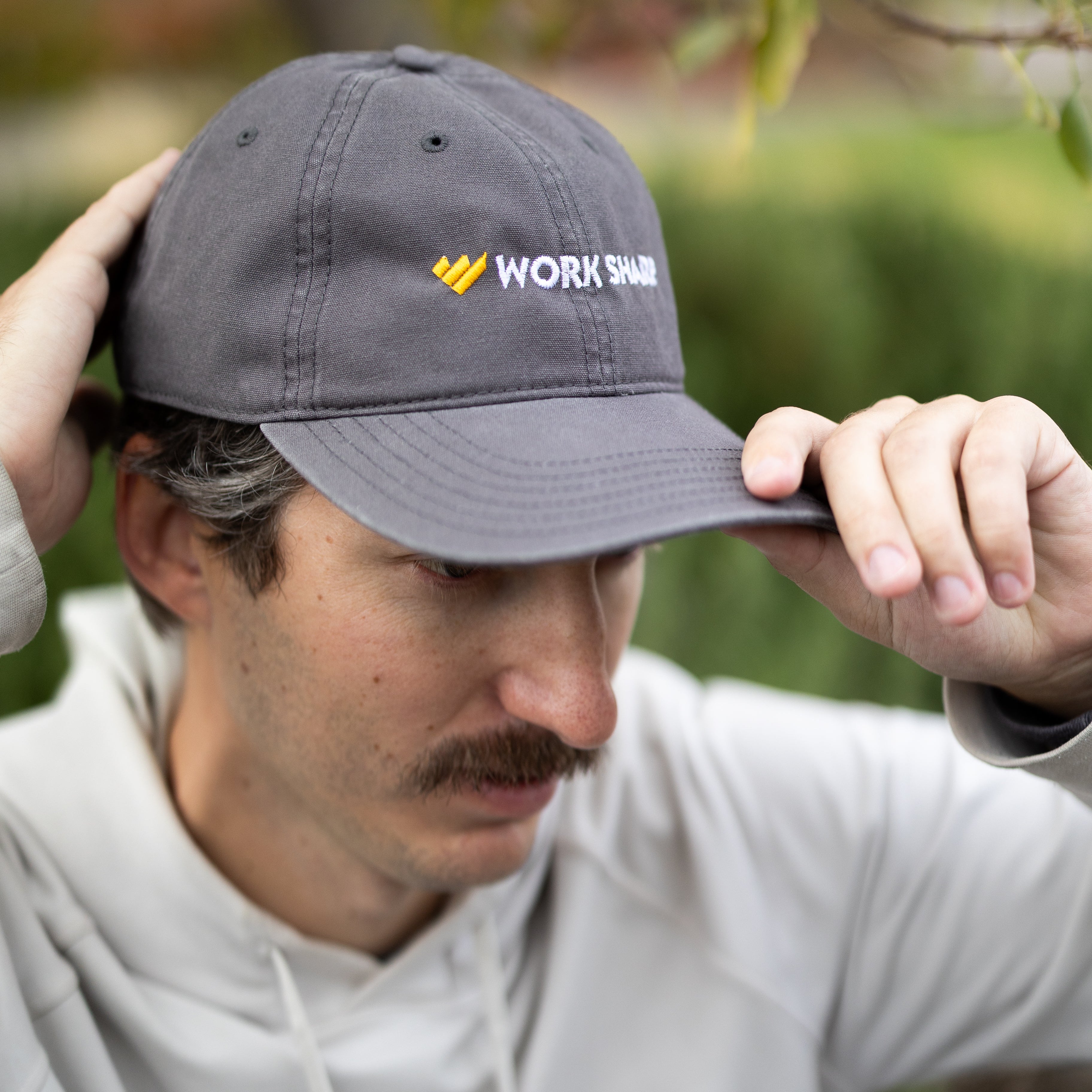 Man wearing a gray cap with 'Work Sharp' logo outdoors