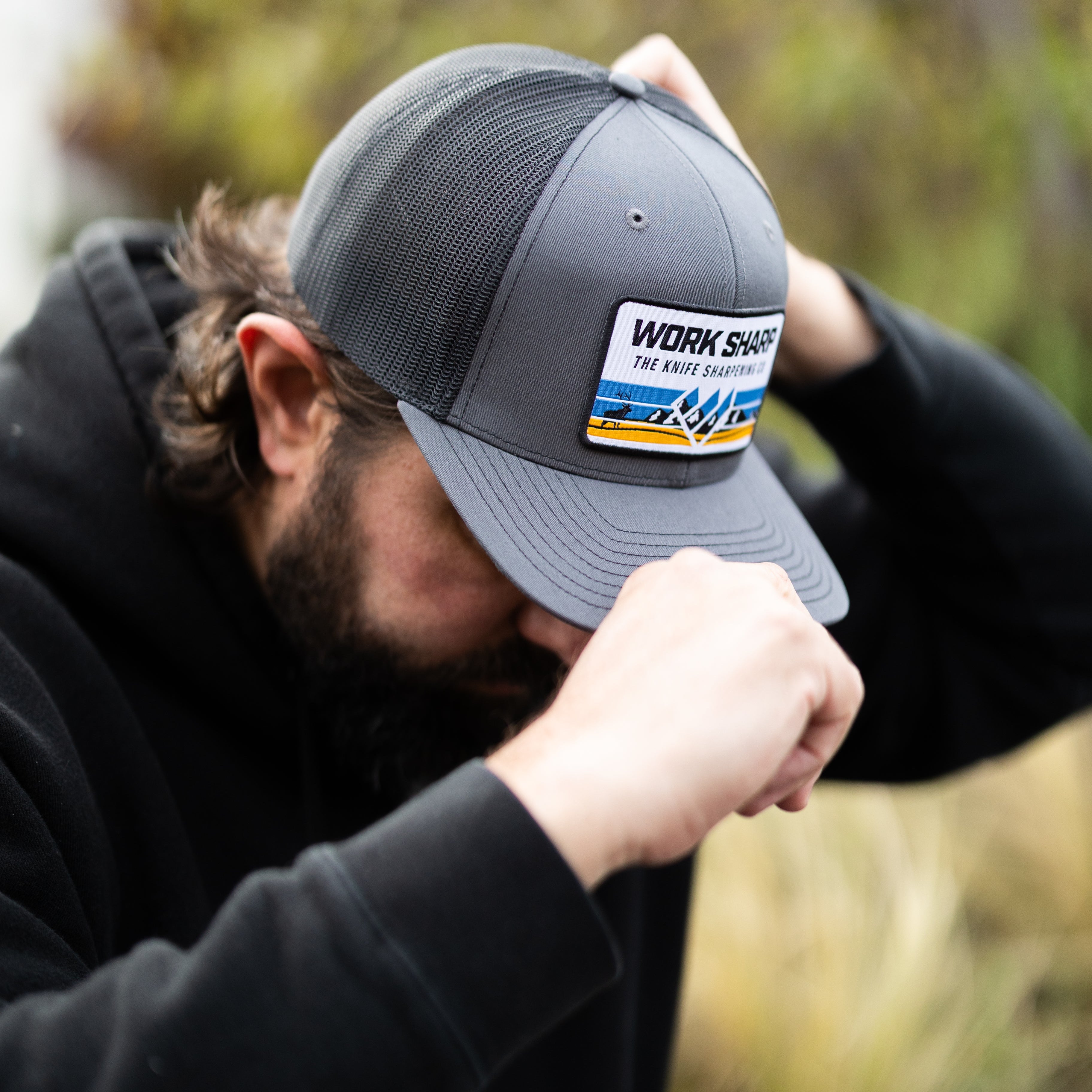 Person wearing a gray cap with Work Sharp branding outdoors