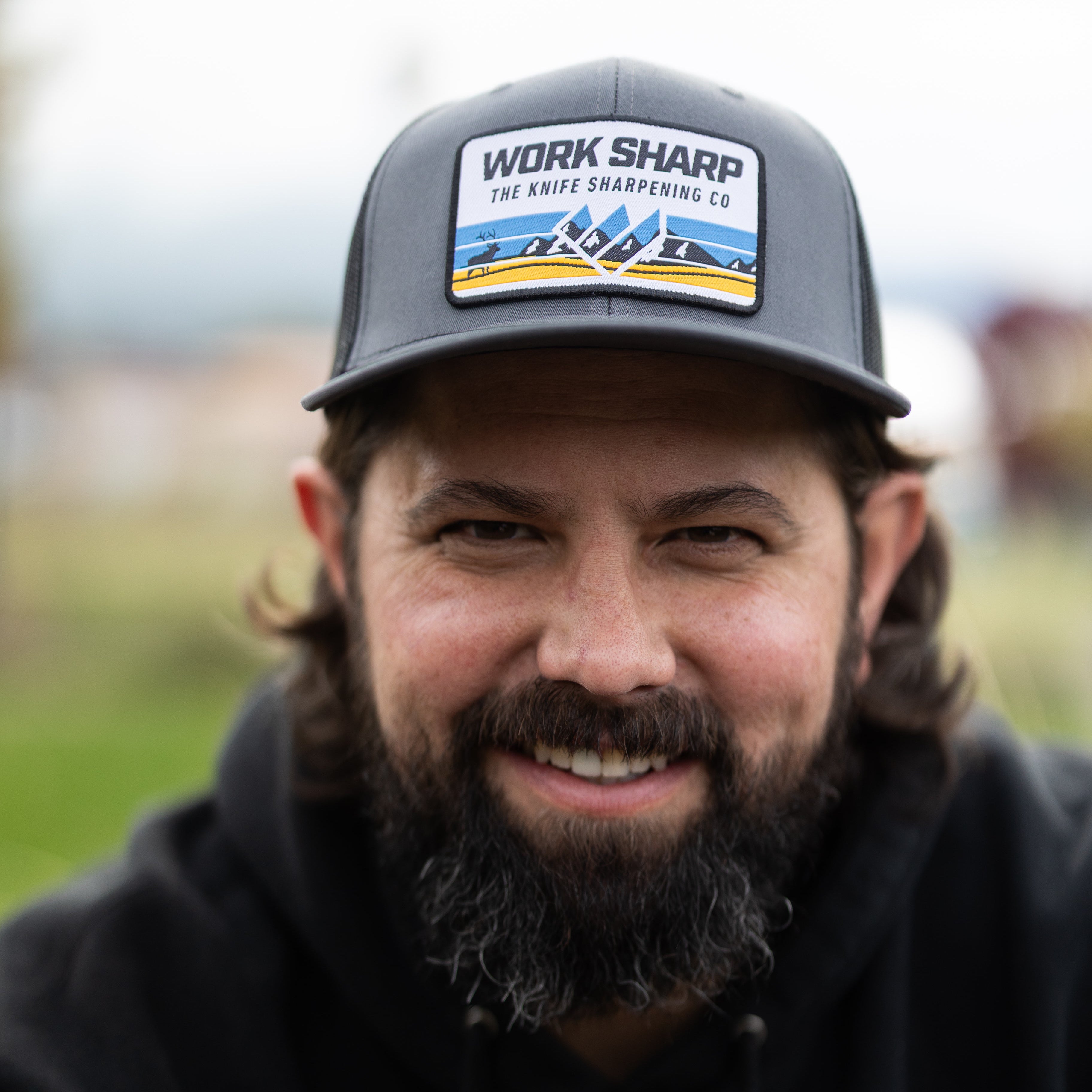 Man wearing a cap with 'Work Sharp' branding and a black hoodie 