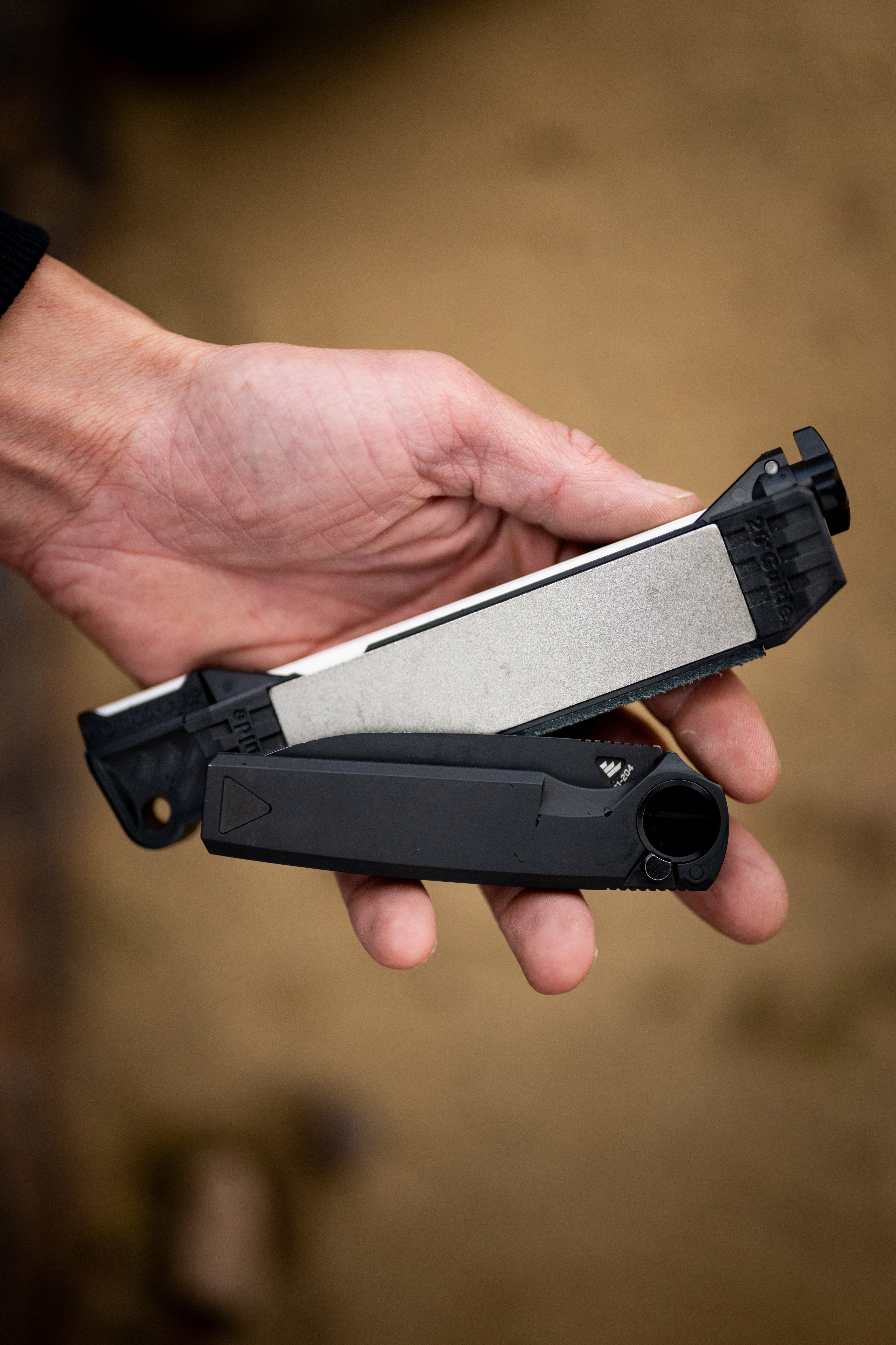 Hand holding a Guided Field Sharpener Blackout | Reserve Series against a blurred background