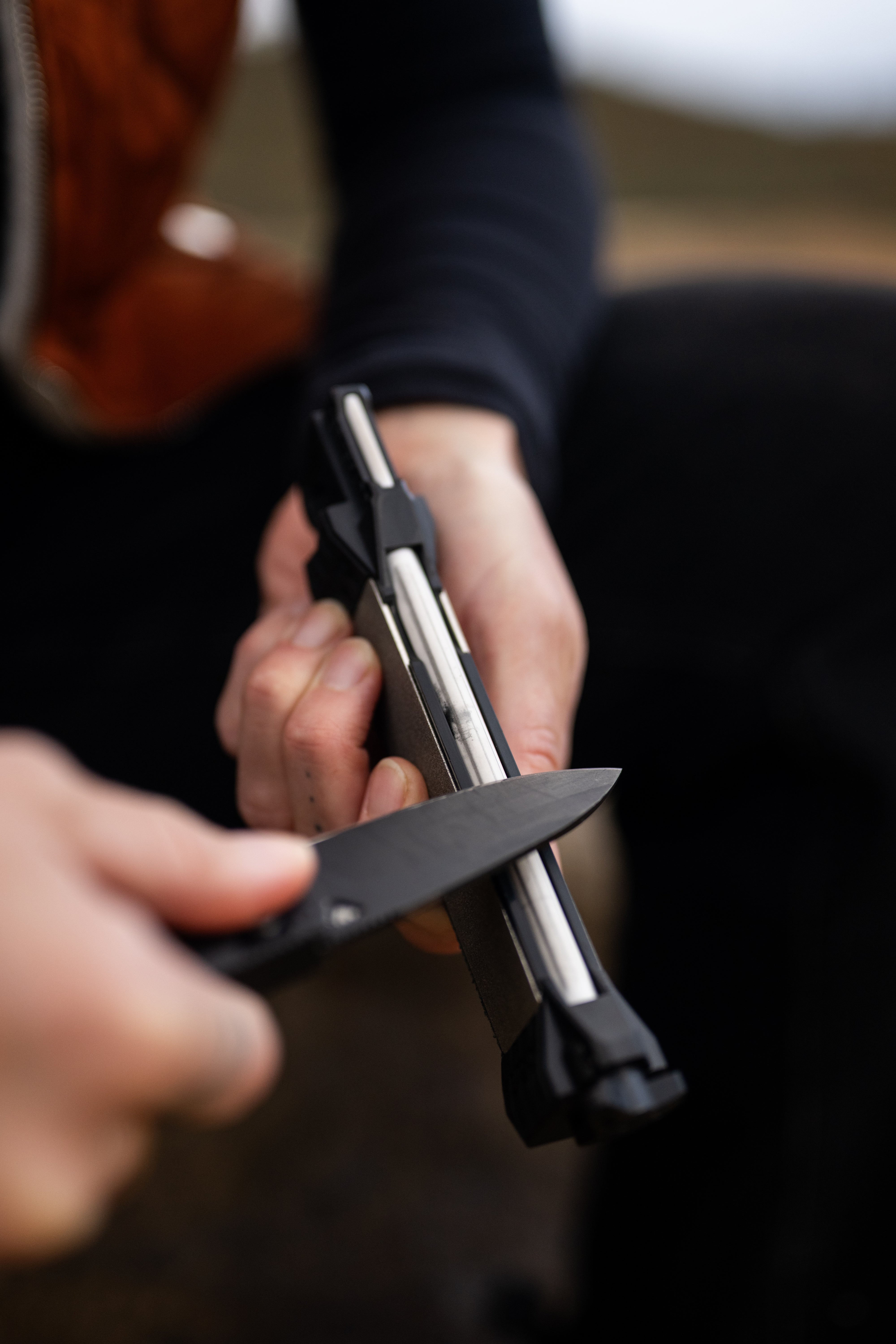 Person holding a knife with Guided Field Sharpener Blackout | Reserve Series in a blurred background