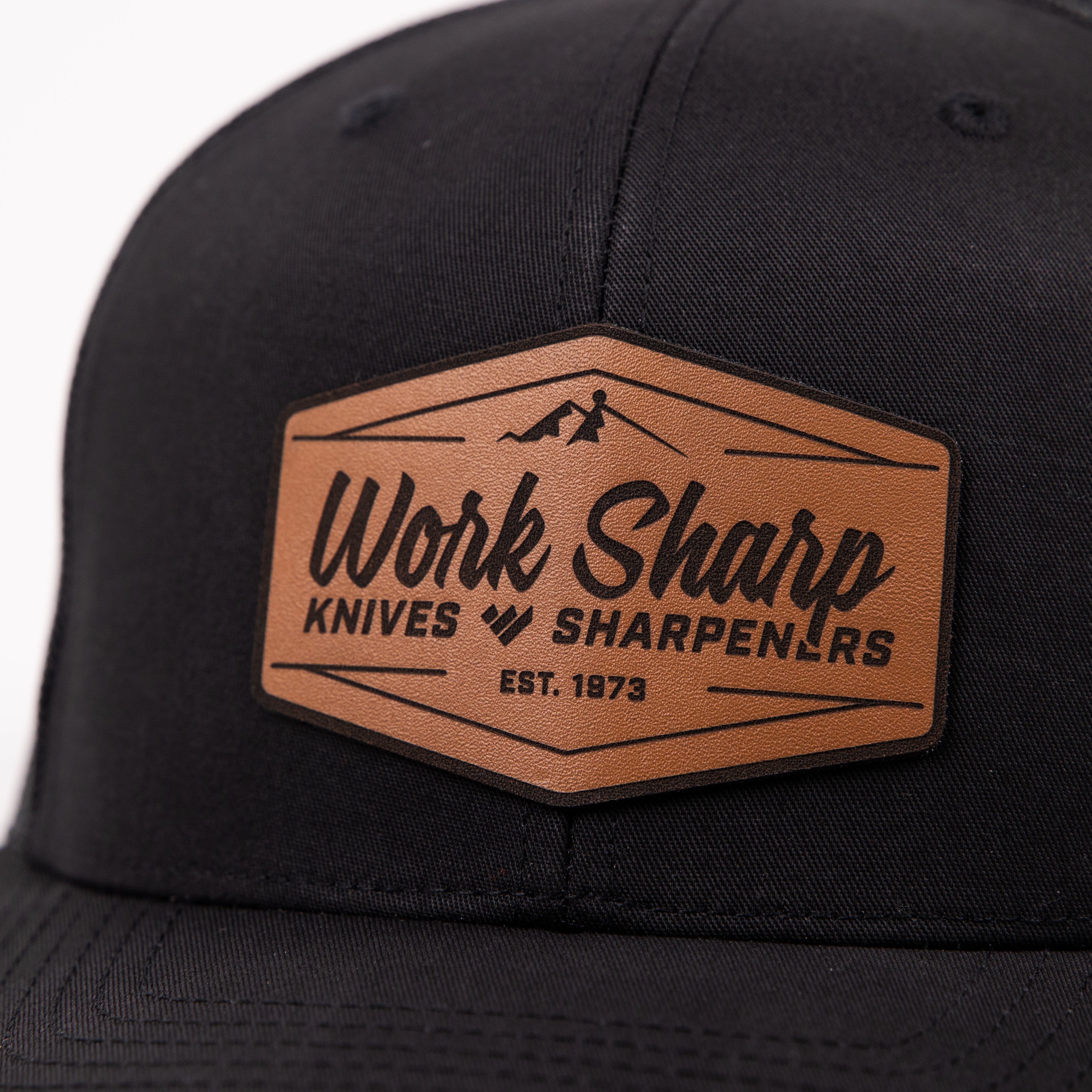 Black cap with a brown leather patch featuring 'Work Sharp Knives Sharpeners' logo.